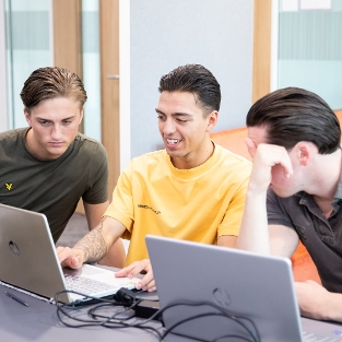3 bedrijfskunde studenten kijken naar een laptopscherm