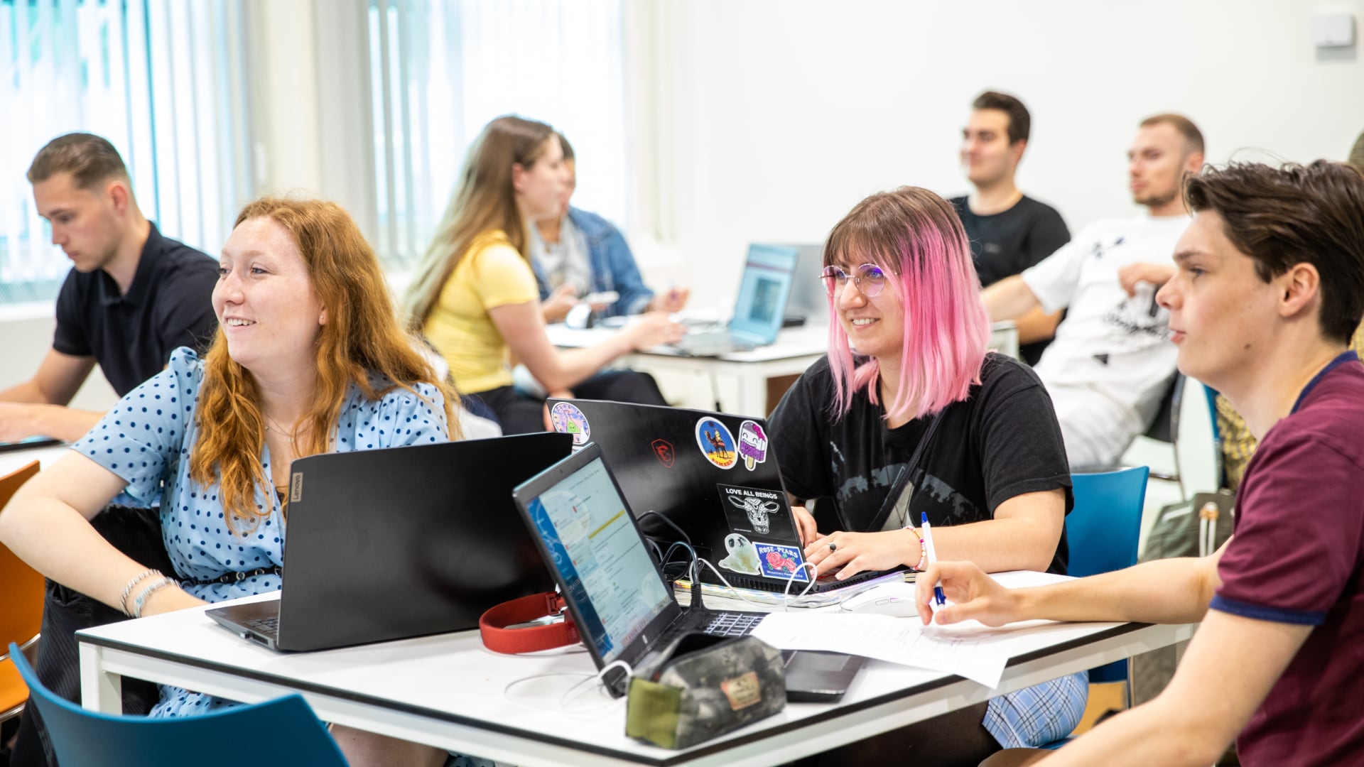Built environment studenten zitten in groepjes in de klas achter hun laptop