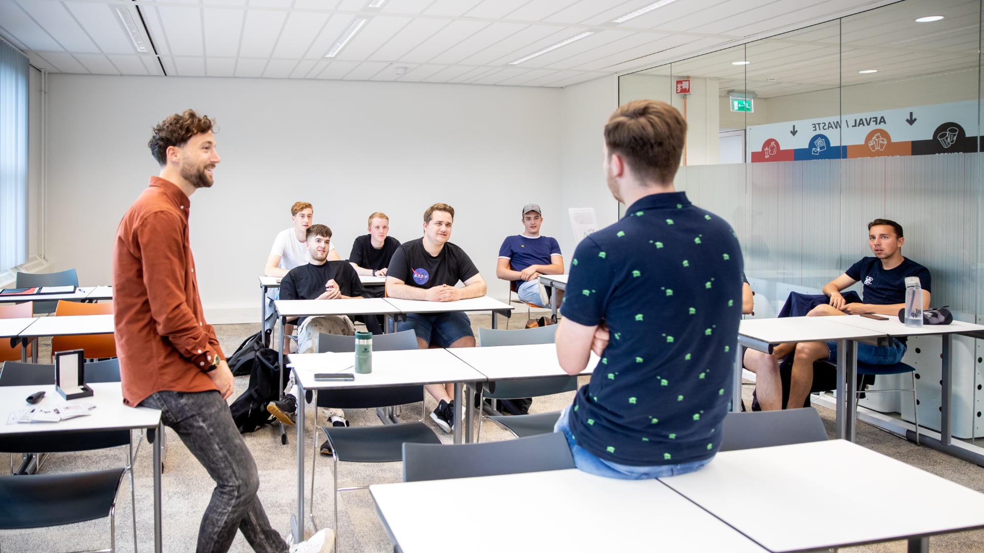 Docent en student staan voor de klas iets te vertellen
